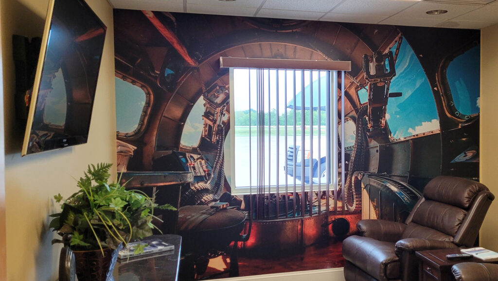 TV room at airport with recliners and graphics on the wall of a World War 2 bomber plane