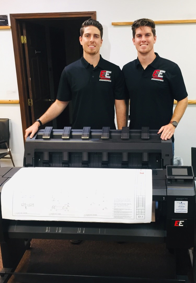 two men standing behind printer
