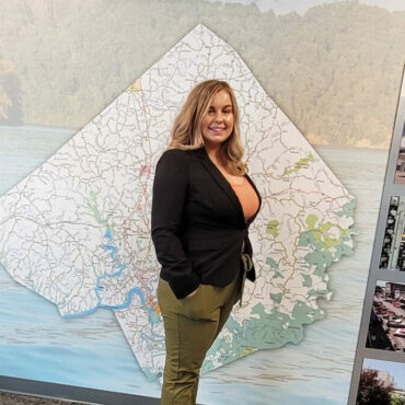 young woman standing in front of wall with graphic of Pulaski County in the background