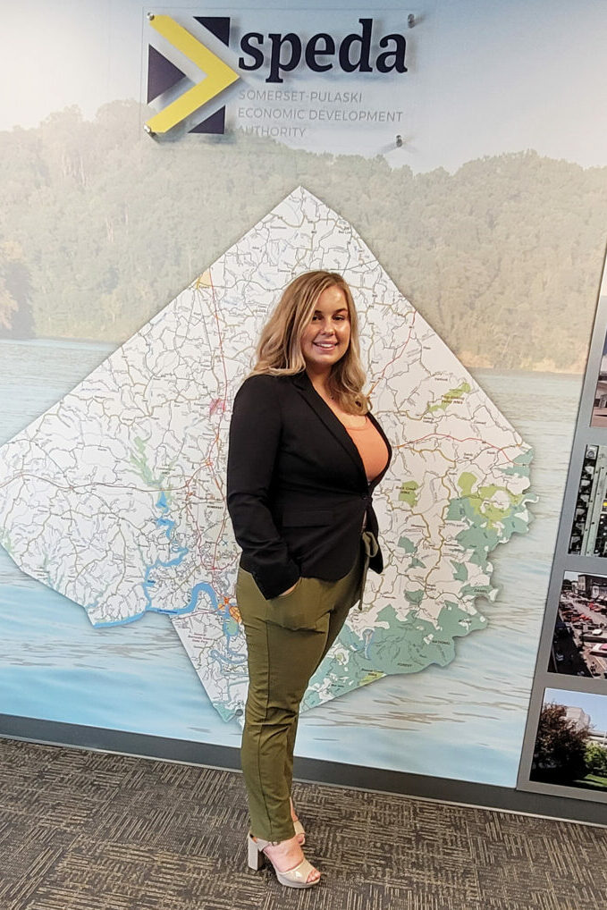 young woman standing in front of wall with graphic of Pulaski County in the background