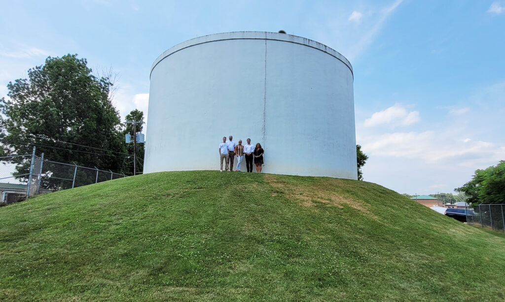 five people standing in front of a water tank