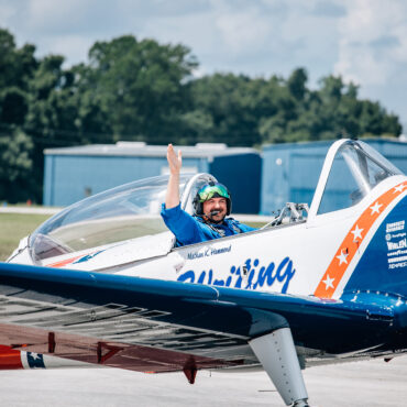 man waving from airplane cockpit