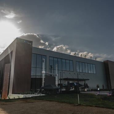 Exterior photo of a distillery with sun shining behind the brick and glass building